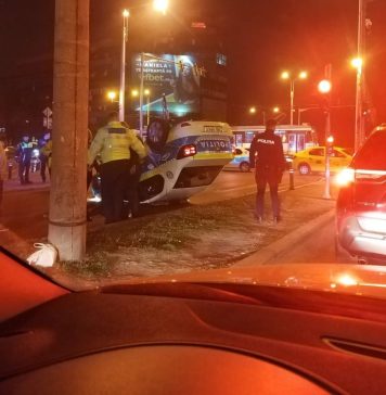 O mașină de poliție aflată în misiune s-a răsturnat într-o intersecție din București, după ce a fost lovită de un taxi – FOTO